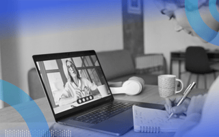 Two women on a Zoom call. The woman on the screen is explaining something while the woman in person is taking notes.
