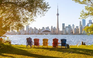 A view of the Toronto skyline from behind five colorful lawn chairs.