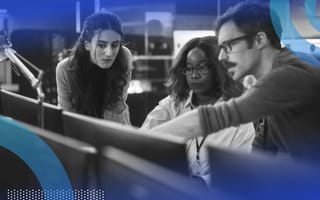 Three software developers collaborating while one points at the desktop screen.