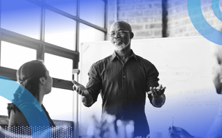 A businessman gives a pitch in front of a whiteboard