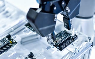 A robotic arm moves circuit boards in a factory