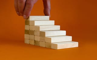 a hand placing a wooden block on top of a stack of wooden blocks