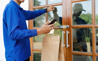 Delivery worker holding a paper bag, knocking on a wooden door.