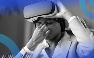 A woman lifting a VR headset off her face while pinching the bridge of her nose from a headache.