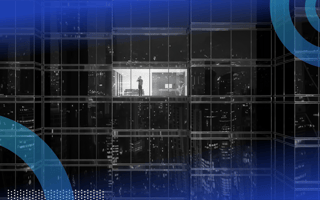 A man talks on his phone in an office building in the lone illuminated window