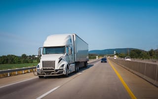 A large white semi-truck drives down a highway.