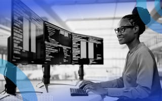 A smiling woman software engineering writing code at her computer with three monitors.