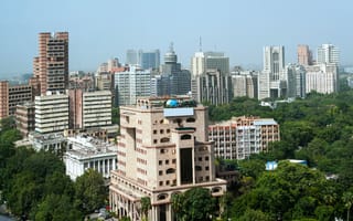 An aerial view of New Delhi featuring several skyscrapers surrounded by trees.