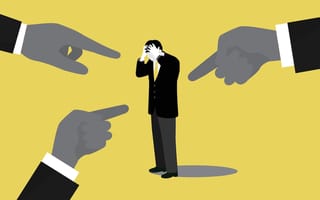 Three fingers point at a man holding his head in embarrassment from being bullied.
