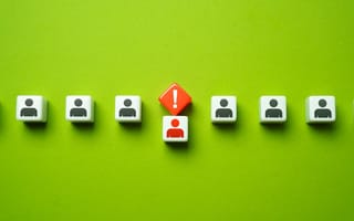 An orange warning sign hangs over the head of one of seven employee avatars.