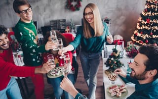 Employees wearing festive sweaters clinking glasses at a holiday party