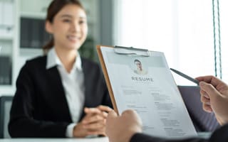 A hiring manager holds an employee's resume while interviewing them.