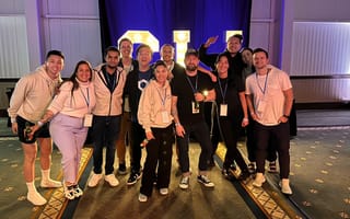 Chainlink Labs team members posing for a group photo in a conference hall in front of a lit sign.