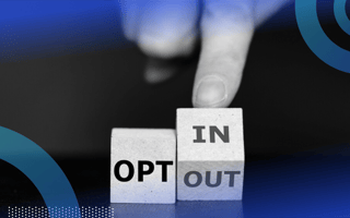 Two wooden cubes, the first reading “OPT” and the second being tilted by a person’s hand so you can see one side that reads “IN” and another that says “OUT.”