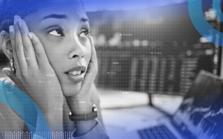 A close-up shot of a stressed tech employee with both hands on either side of her face in front of two monitors with code on them.