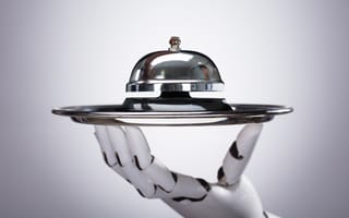 Robotic hand holding service bell against grey background.