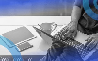 An engineer works on a laptop with a tablet and phone nearby