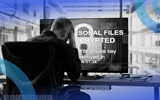 A man sits in distress at a computer terminal that says his files have been hacked