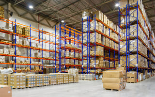 Boxes are stacked on tall shelves in a shipping warehouse.