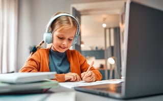 A child is shown using a laptop and wearing headphones.