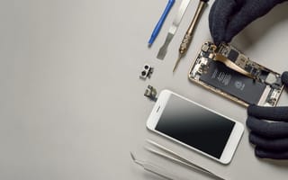 a photo of a disassembled smartphone and a pair of hands working on it.