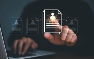 A hand reaches toward an illustration of a document with an icon of a person at the top to depict the hiring process.