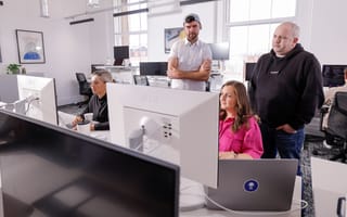 Three Benchling employees look at information displayed on a computer monitor at the company’s Belfast office