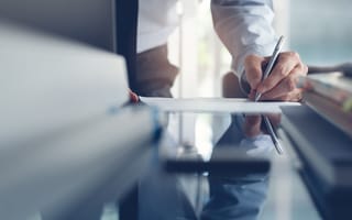 A person signing a document is pictured.