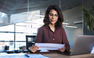 A woman looking over documents in an office setting is pictured.