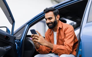 A person checks their phone while sitting in a car.