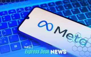 A smartphone sitting on a laptop showing Meta's logo is shown.