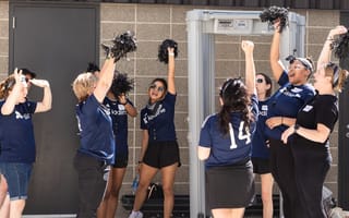 Iodine Software team members raise pom poms into the air while wearing Iodine Software-branded T-shirts