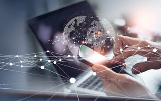 Person using smartphone and laptop with a digital globe and cybersecurity network overlay, representing global information security and data protection.