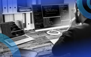 Software developer writing code and reviewing multiple monitors