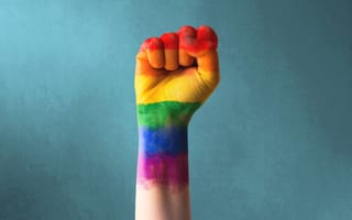 An image of a clenched fist painted in rainbow colors, representing the fight for LGBTQIA inclusion