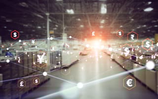 Blurred warehouse interior with digital overlay of global currency symbols like dollar, euro, yen and pound. Network lines connect symbols, conveying financial connectivity.