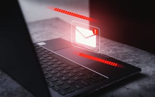 A digital illustration of an envelope with a red exclamation mark icon hovers over a laptop keyboard to represent email security.