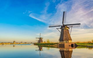 11 Top Tech Companies in the Netherlands Windmills stand along the water with a bright blue sky in the background.