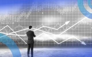 A man in a suit ponders graph trend lines