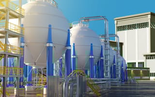 Industrial scene with large white spherical tanks supported by blue beams, surrounded by pipes and yellow railings, set against a clear blue sky.