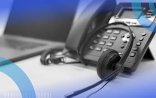 A business phone with a headset and a laptop