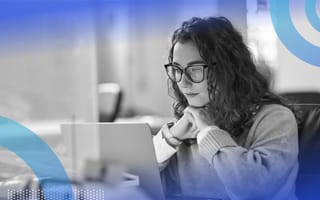 A young woman with glasses looks intently at a computer