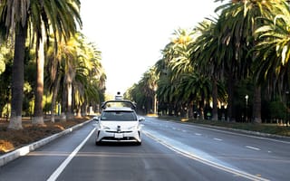 Nuro vehicle shown driving on road lined with palm trees.