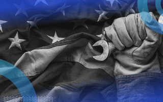 A gloved hand holds a wrench in front of an American flag