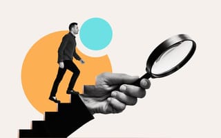 A job applicant climbs up an arm holding a magnifying glass.