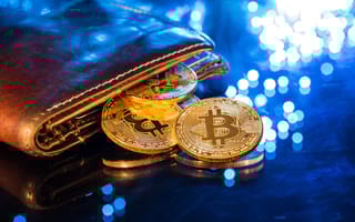 Gold coins featuring the Bitcoin symbol are falling out of a brown leather wallet to depict cryptocurrency.