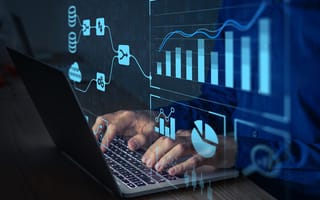 A digital illustration of various charts hovers over a laptop keyboard as a pair of hands types.