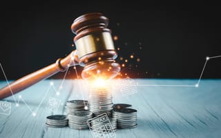 A wooden judge’s gavel strikes a stack of coins on a table, with glowing digital icons representing taxes, documents and financial data overlaid, symbolizing law enforcement and regulation of financial activity.
