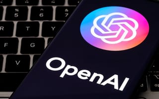 OpenAI logo on a smartphone resting on top of a laptop keyboard.