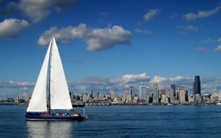 A sailboat sails past the Seattle skyline on the Puget Sound